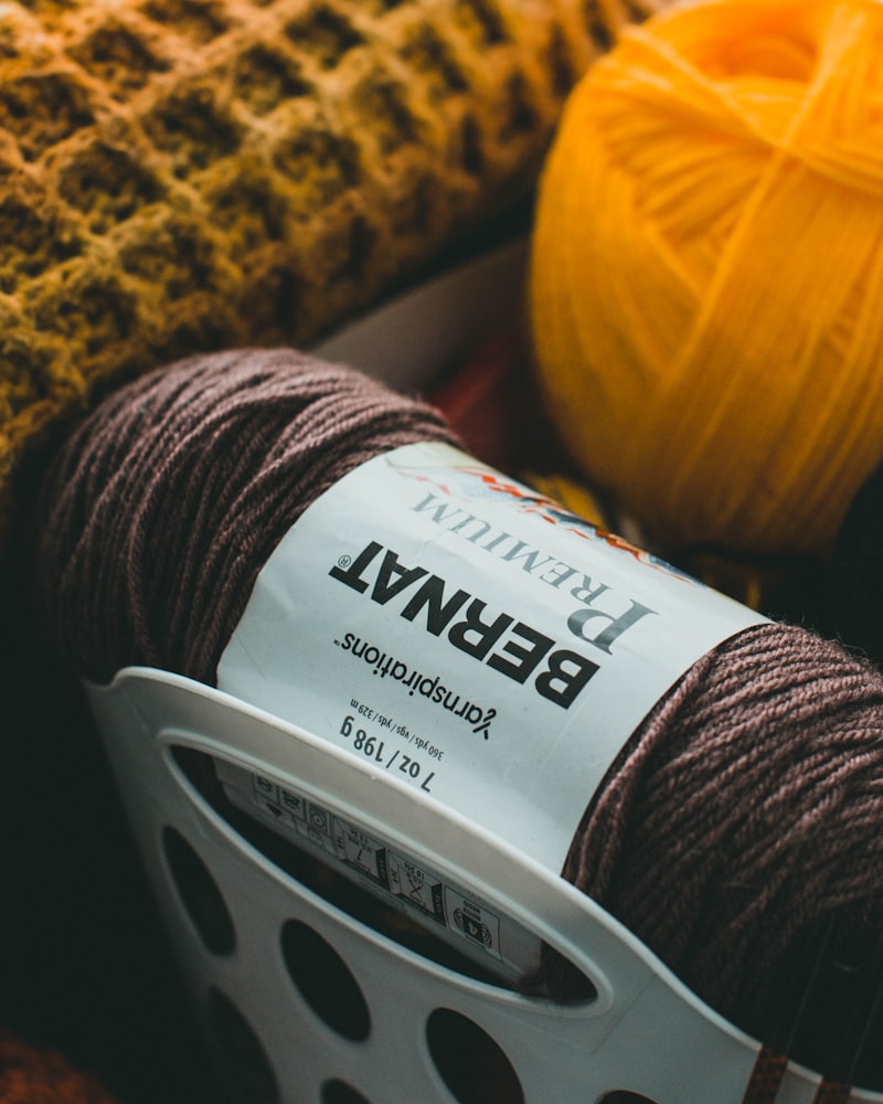 Yellow and red yarn on a dark textile surface — warm craft still life