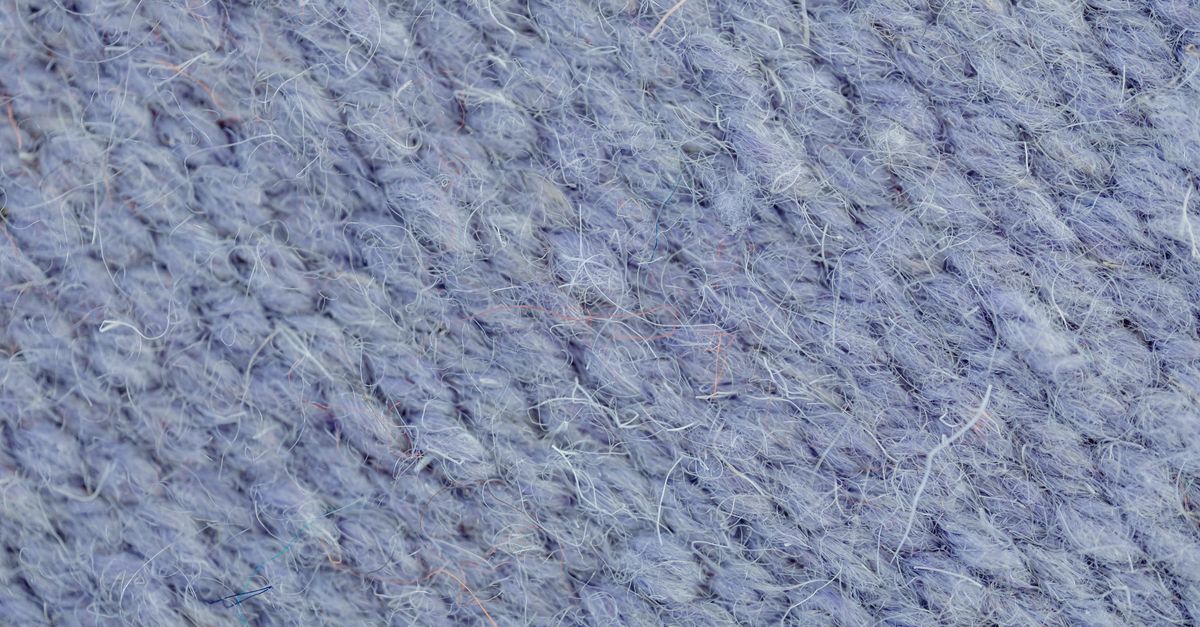 Close-up of blue knitted wool fabric showing detailed stitch texture